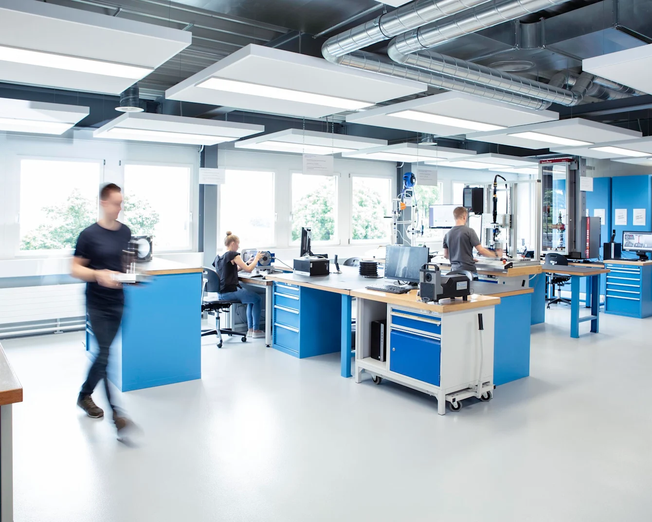 Tre ingeniører samarbeider om ulike tester i et velutstyrt laboratorium, med klar utsikt over både teamet og testutstyret.