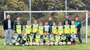 Jugendmannschaft des FV Schnürpflingen mit Trainern vor einem Fußballtor, ausgestattet mit neuen Fußbällen und Trainingsleibchen.