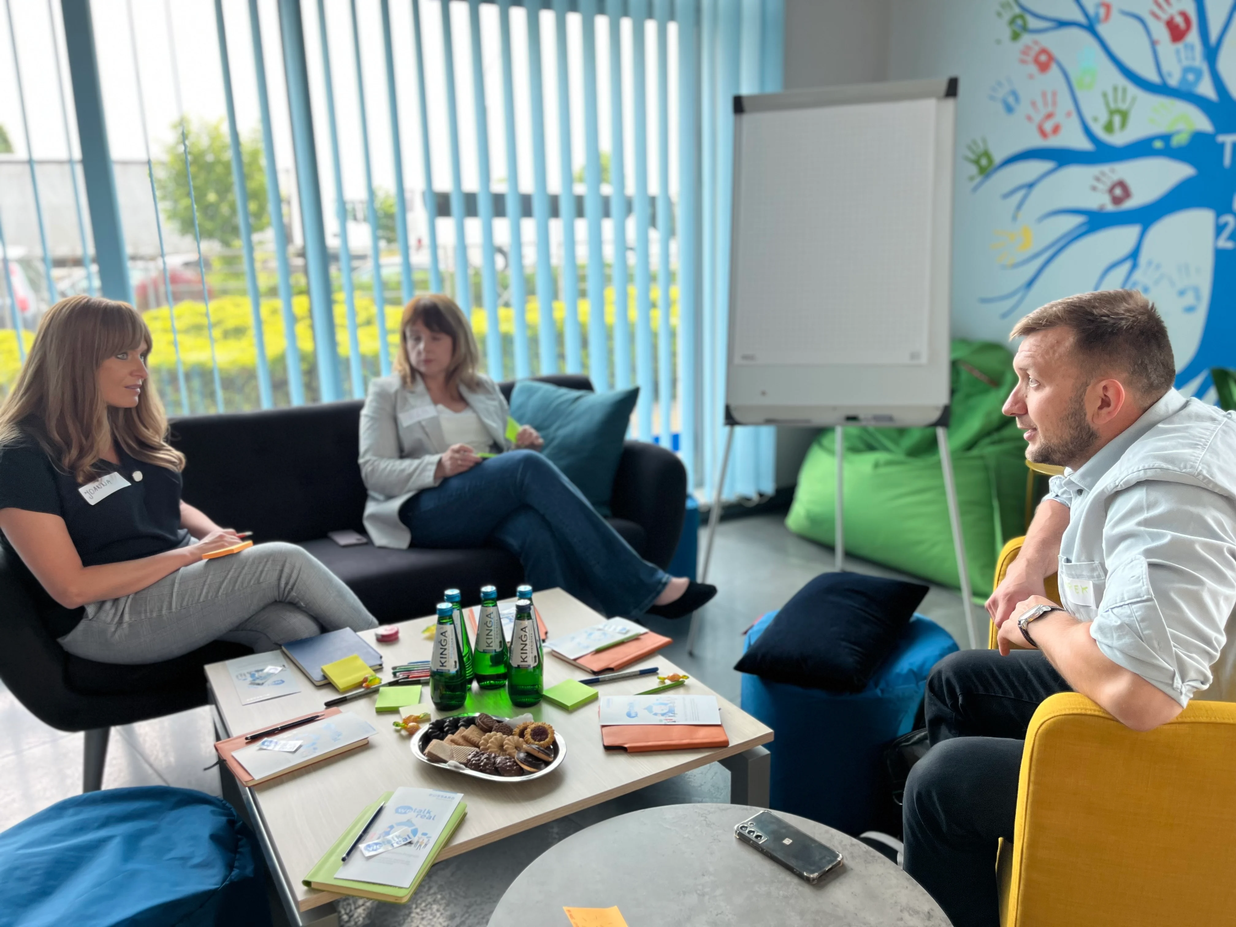 A group of individuals gathered around a table in a room adorned with vibrant, colorful walls.