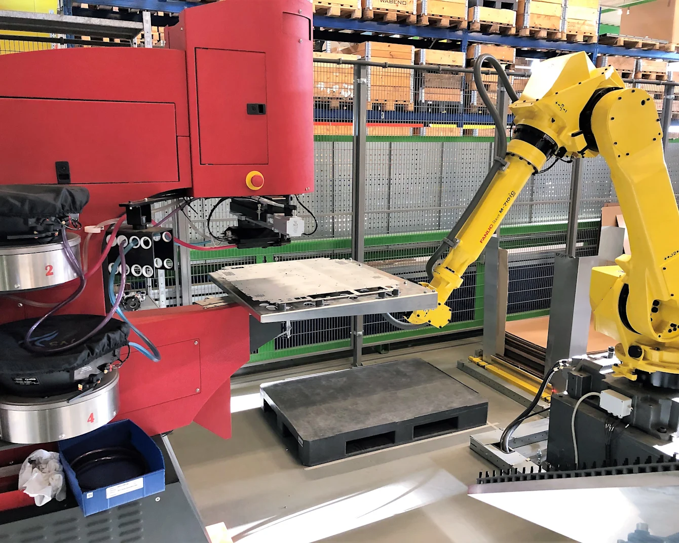 Eine rote Haeger-Einpressmaschine arbeitet mit einem gelben Roboterarm, um die Installation von Einpressbefestigern zu automatisieren.