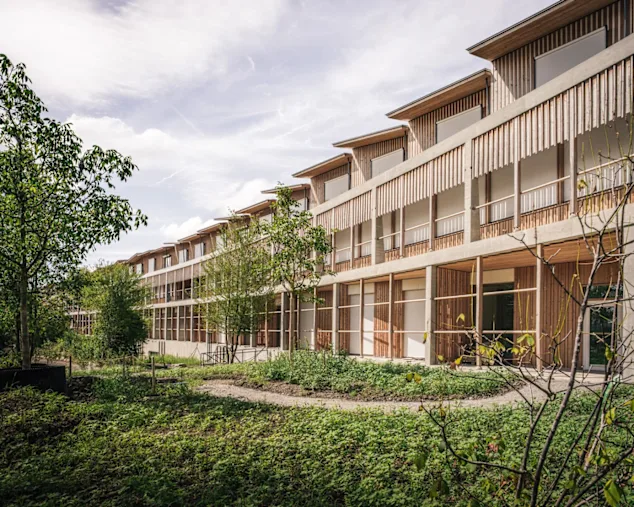 A wooden building with windows, representing the Zurich Children's Hospital, has a modern wooden façade.