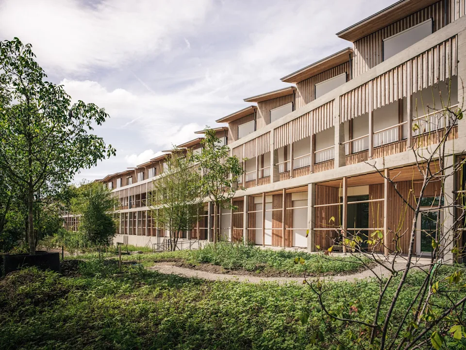 Ein Holzgebäude mit Fenstern, das das Kinderspital Zürich repräsentiert, zeigt eine moderne Holzfassade.