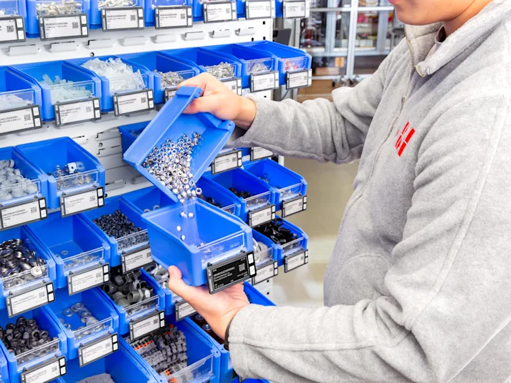 A man is refilling a SmartLabel Cloud bin by moving nuts from one bin to another.