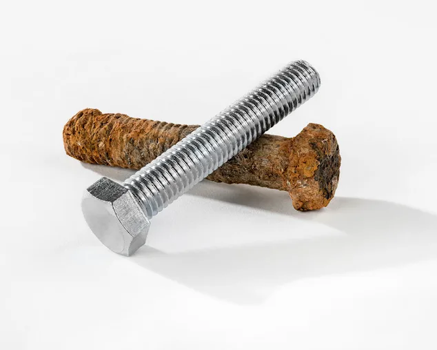 Eine metallische Schraube und eine korrodierte auf weissem Hintergrund, zur Veranschaulichung im Vergleich.