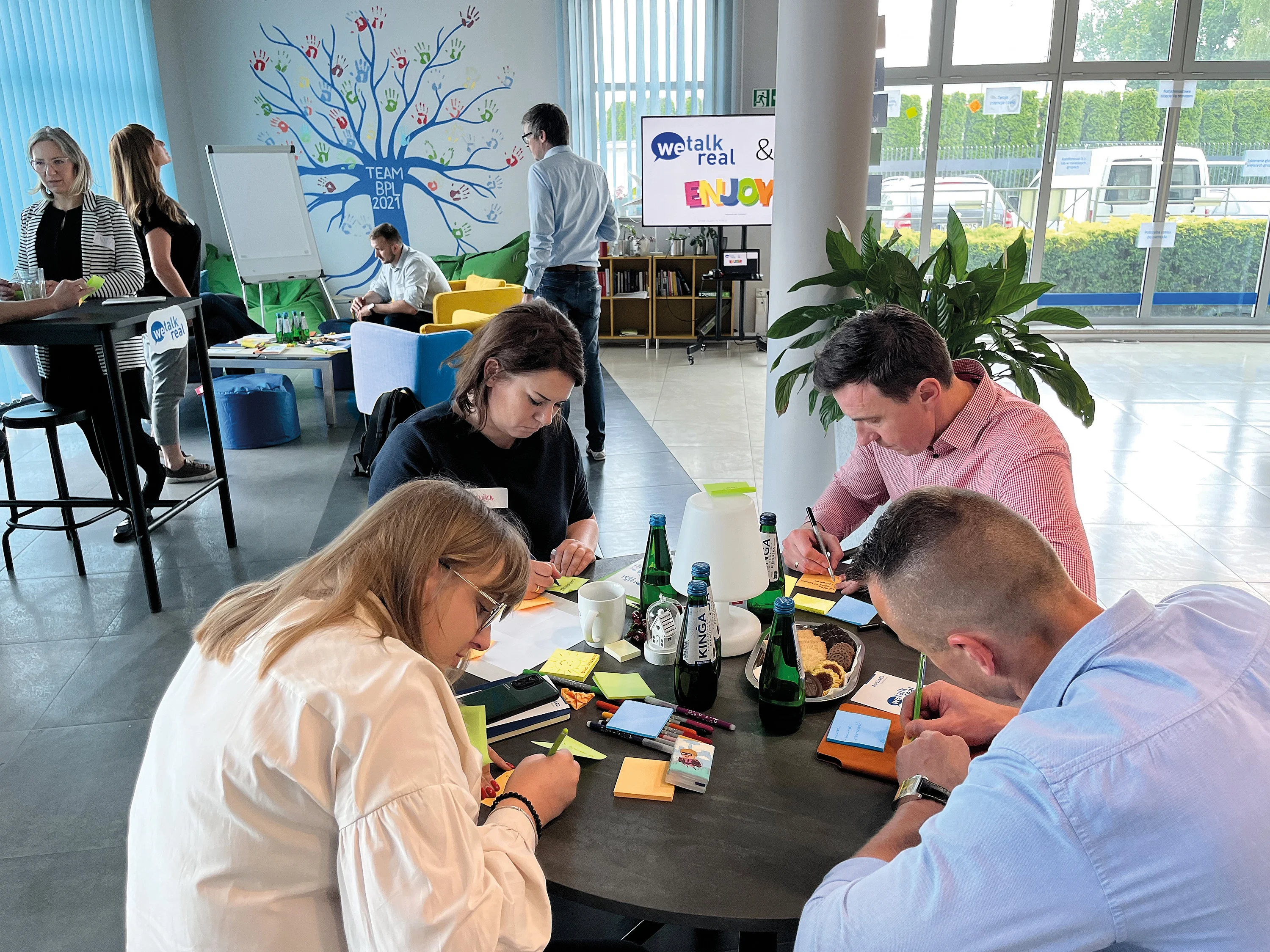 A group of individuals collaborates at a table, surrounded by colorful sticky notes, engaged in a brainstorming session.