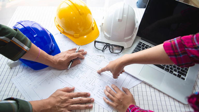 People looking at construction plans on a desk