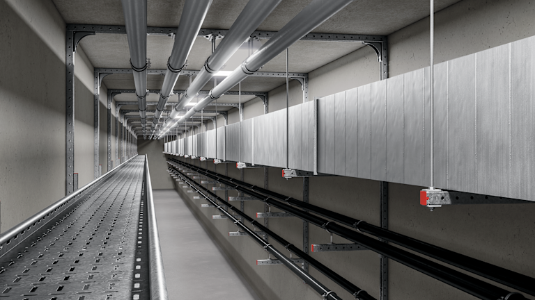 Long utility corridor with pipes, cable trays, and ducts mounted on wall brackets, creating an organized service installation pathway in a concrete tunnel.