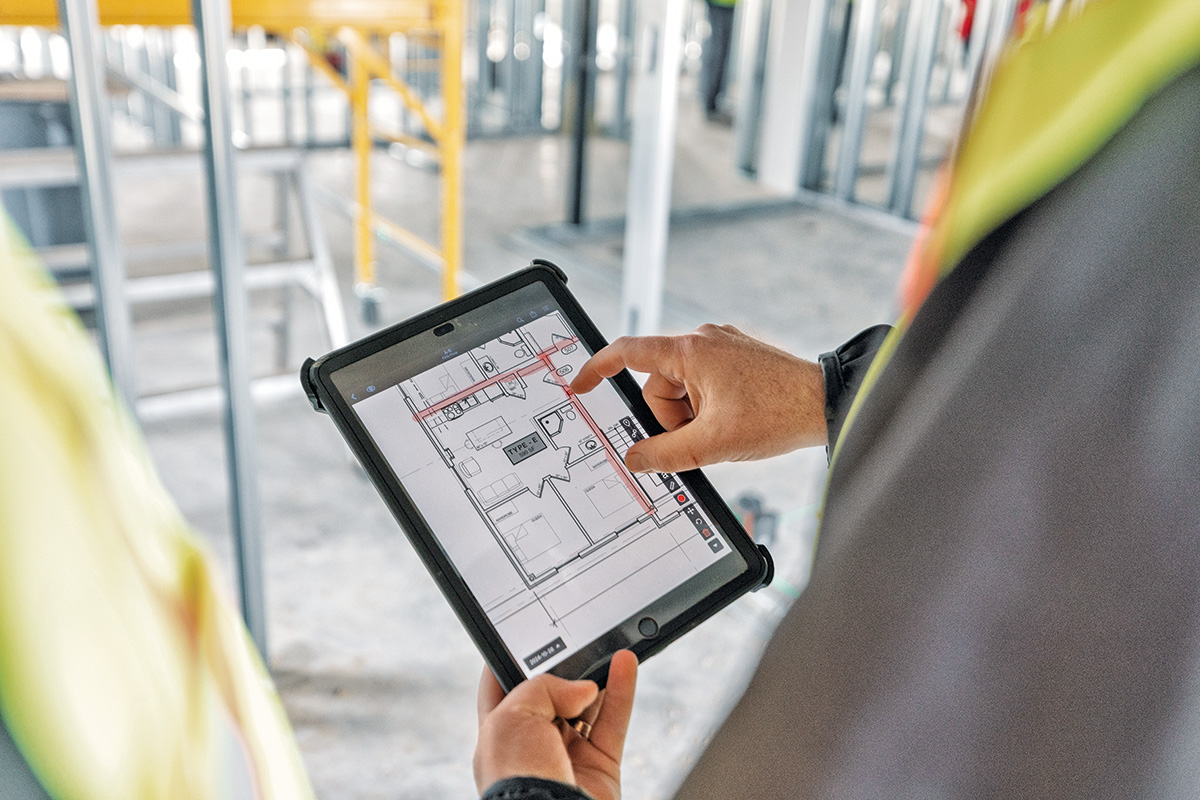 A construction worker looks at a detail on project's blueprint using Fieldwire's jobsite management software on mobile.