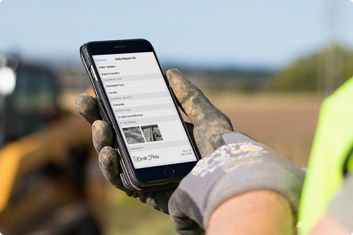Fieldwire being shown on an iPhone at a construction site. The user is looking at a form and filling out their time sheet.