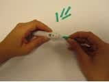 In the picture, there are hands placing a green lancet into a lancet pen.