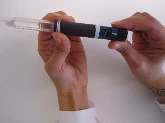 In the picture, the left hand is holding the insulin pen in place while the right hand sets the desired dose by turning the end of the pen.
