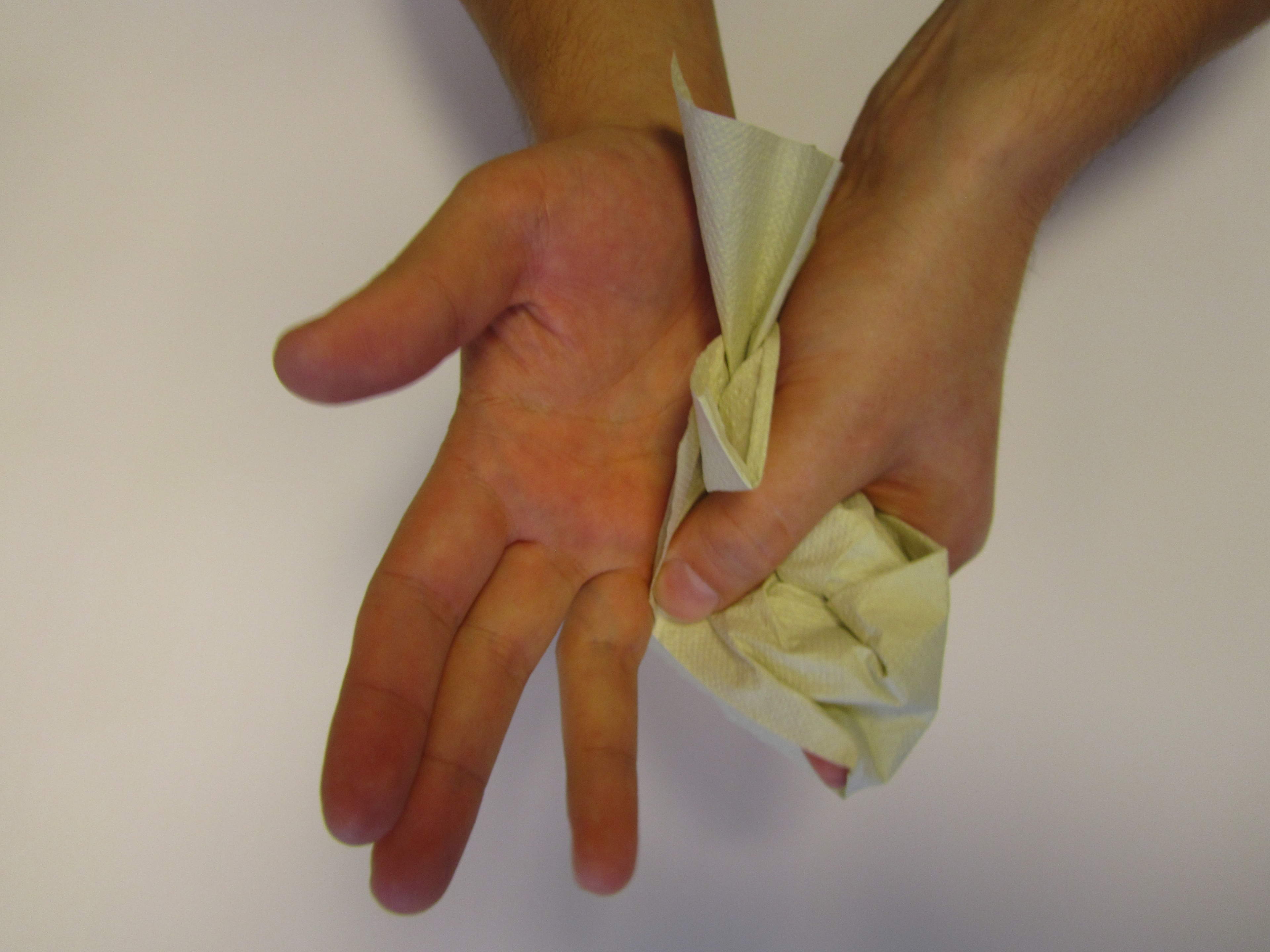 In the image are hands that are being dried with disposable paper towels.