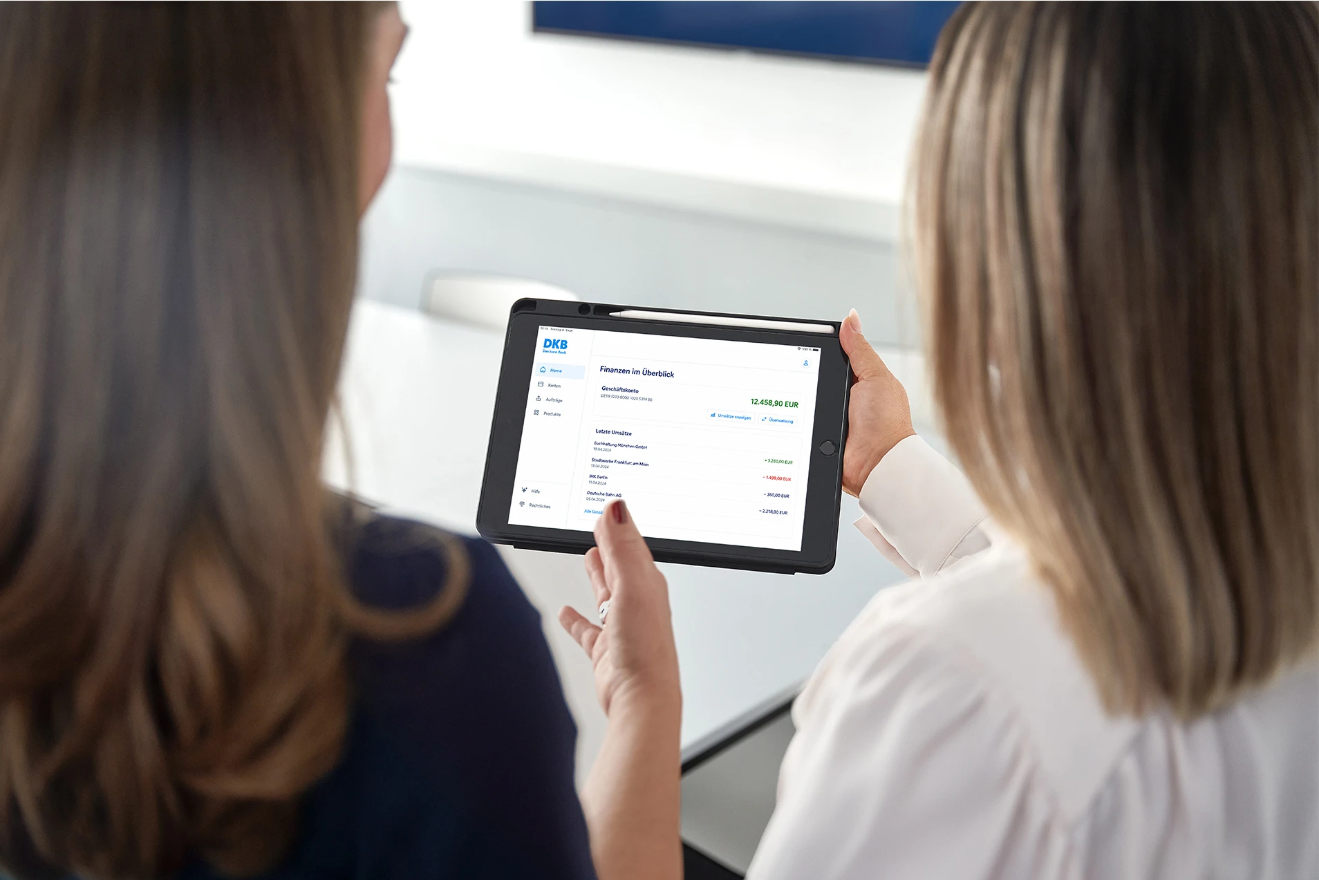 Zwei Personen betrachten DKB-Finanzübersicht auf Tablet