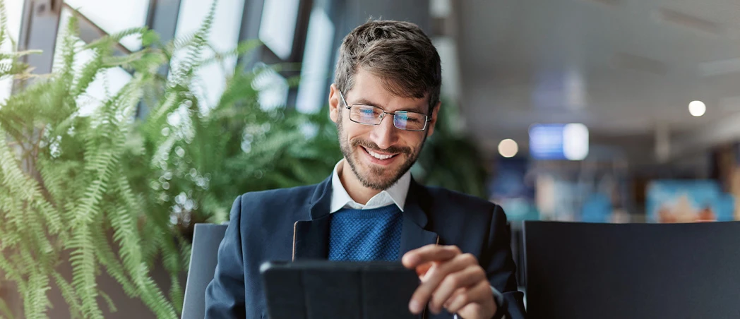Ein Mann sitzt in einem Stuhl mit einem Tablet in der Hand