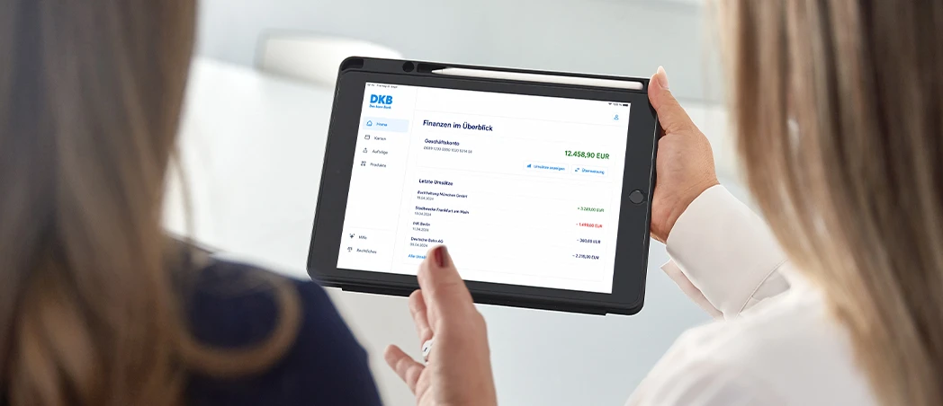 Zwei Personen betrachten DKB-Finanzübersicht auf Tablet