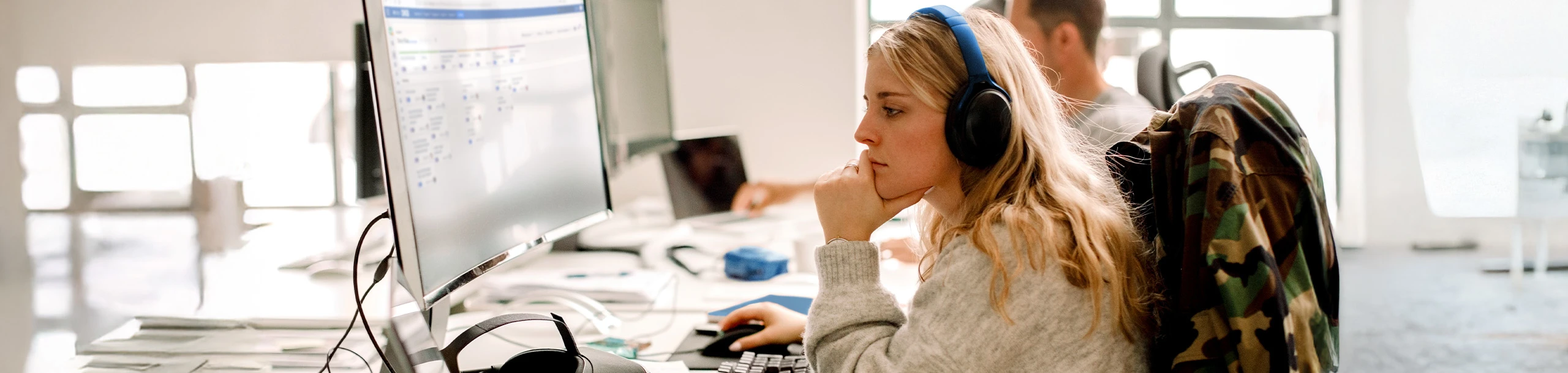 Frau mit Headset arbeitet konzentriert am Computer im Büro