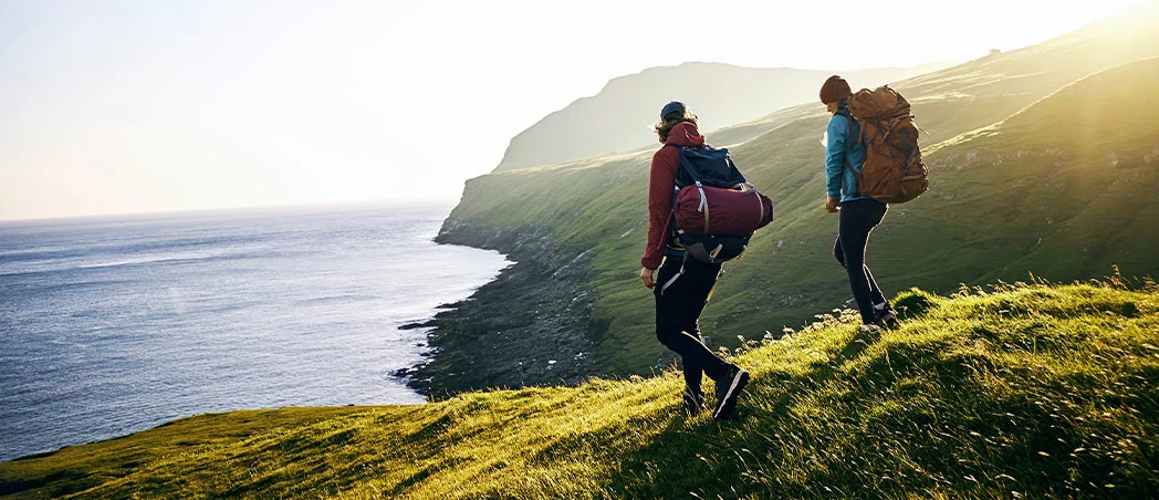 Zwei Personen wandern in einer grünen Landschaft
