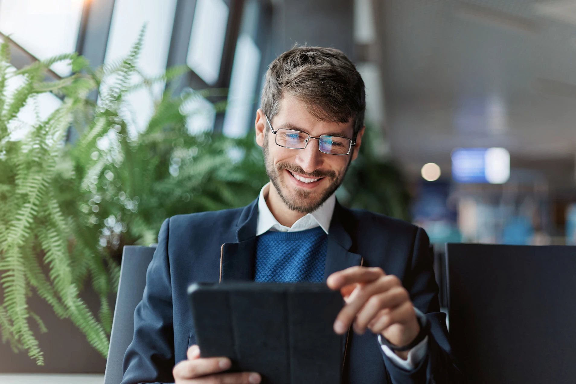 Ein Mann sitzt in einem Stuhl mit einem Tablet in der Hand