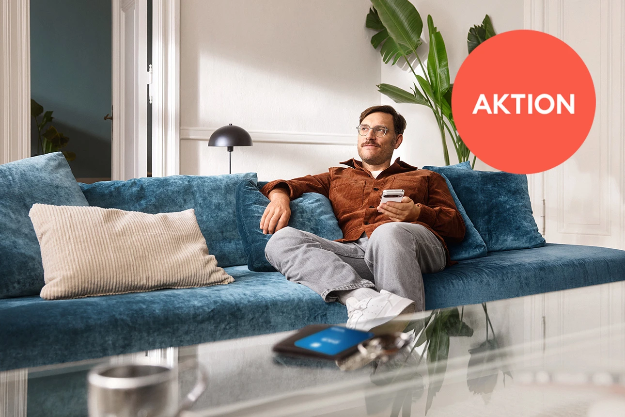 Ein Mann mit Smartphone sitzt auf der Couch