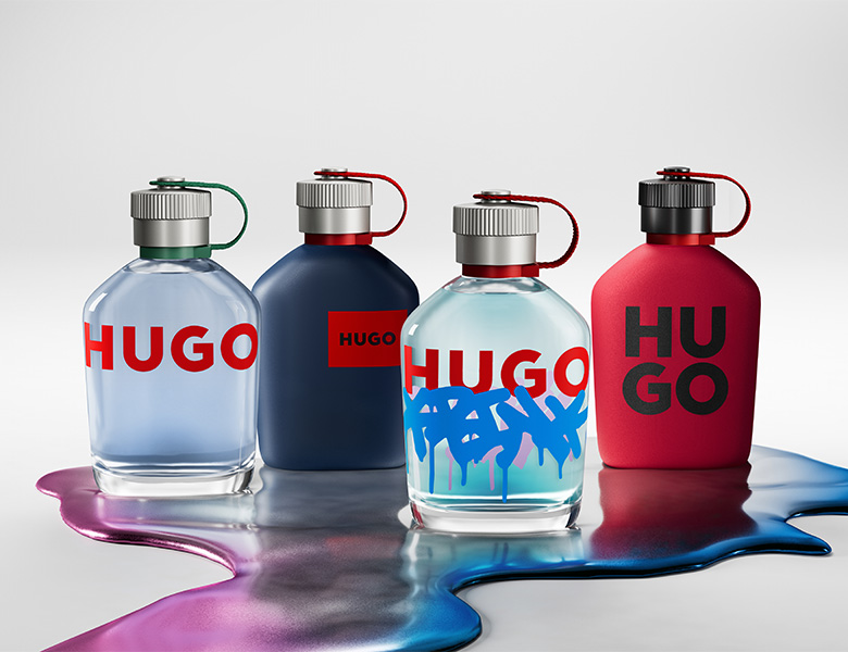 Her ses et billede med fire parfumeflakoner fra HUGO placeret mod en lys baggrund. Flakonerne vises i forskellige farver og designs, herunder gennemsigtige og matte udgaver med det karakteristiske “HUGO”-logo.