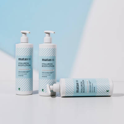Her ses en lyseblå og hvid baggrund med tre blå og hvide hyaluron produkter fra Matas Striber.