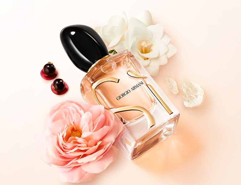 Her ses Giorgio Armani Sì-parfumen omgivet af blomster og bær på en lys baggrund.