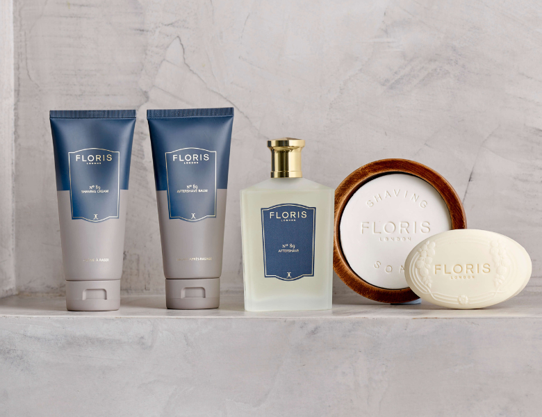 Floris London barberingsprodukter står opstillet på en lys stenhylde, herunder shaving cream, aftershave balm, aftershave og barbersæbe.