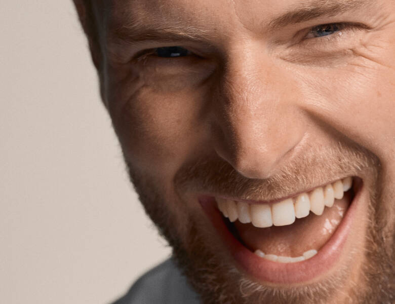 Her ses ansigtet af en smilende og grinende mand.