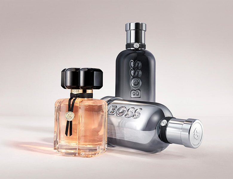 Her ses et billede med tre parfumeflakoner fra BOSS placeret mod en lys baggrund. Der ses en BOSS Bottled-flakon til kvinder samt to BOSS Bottled-flakoner til mænd i forskellige farver.