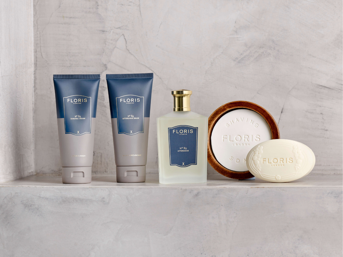 Floris London barberingsprodukter står opstillet på en lys stenhylde, herunder shaving cream, aftershave balm, aftershave og barbersæbe.