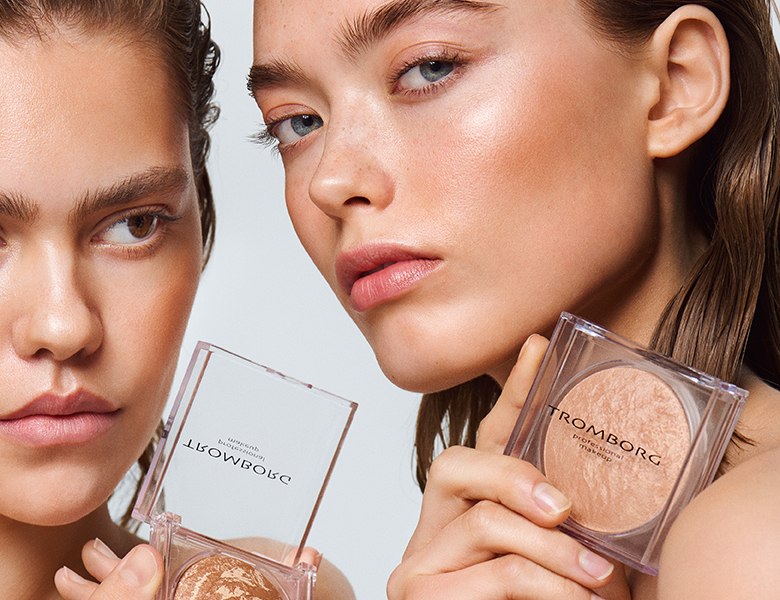 Nærbillede af to modeller med makeup. Den ene holder et Tromborg Professional Makeup pudderkompakt.