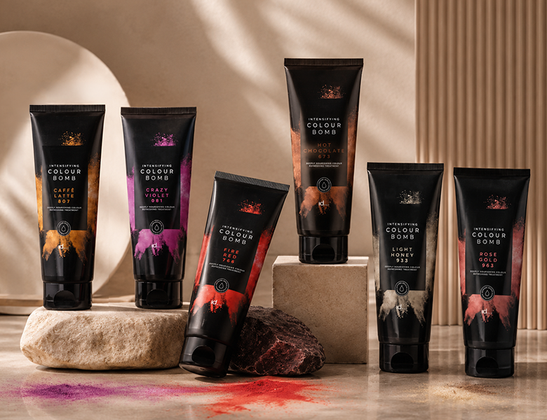Her ses et billede med hårfarveprodukter fra IdHAIR placeret på sten mod en varm, beige baggrund. På produkterne står blandt andet “Intensifying Colour Bomb”, og farverne inkluderer blandt andet “Caffé Latte”, “Crazy Violet”, “Fire Red”, “Hot Chocolate”, “Light Honey” og “Rose Gold”.