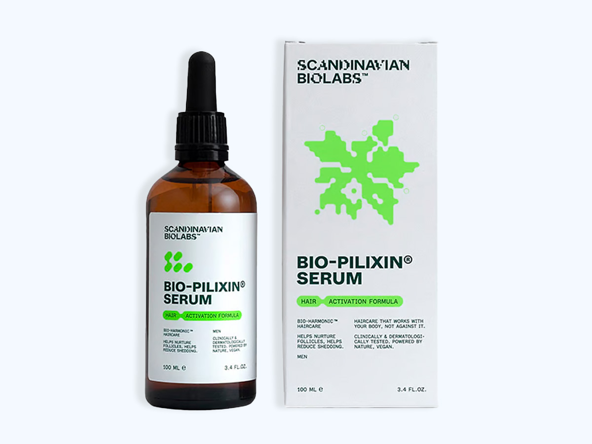 Her ses et billede af et Bio-Pilixin Serum fra Scandinavian Biolabs mod en lys baggrund. Til venstre står en brun glasflaske med pipette, og til højre ses produktets æske. På emballagen står blandt andet “BIO-PILIXIN® SERUM”, “Hair Activation Formula” og “Scandinavian Biolabs”. Produkterne er placeret enkelt og med fokus på serumflasken og emballagens grønne grafiske element.