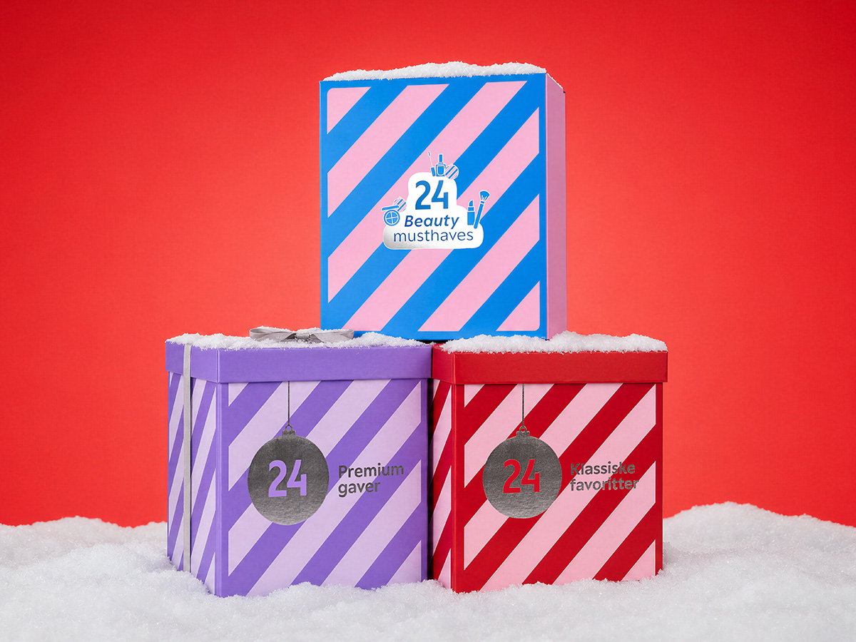 Tre stablede julekalendere i sne: Blå med '24 Beauty musthaves', lilla med '24 Premium gaver', og rød med '24 Klassiske favoritter'.