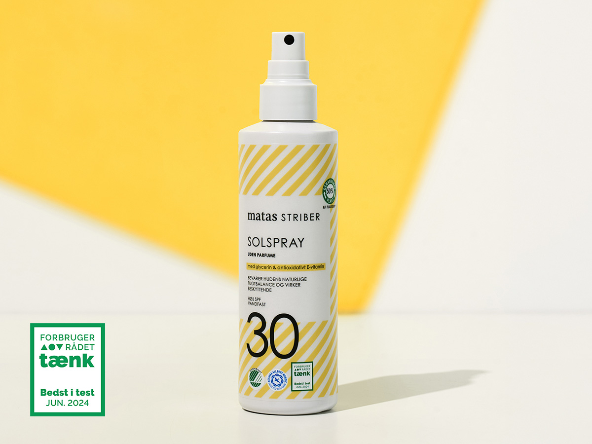 Her ses en Matas Striber solspray SPF 30 i hvid og gul emballage på en gul baggrund sammen med mærket “Bedst i test” fra Forbrugerrådet Tænk.