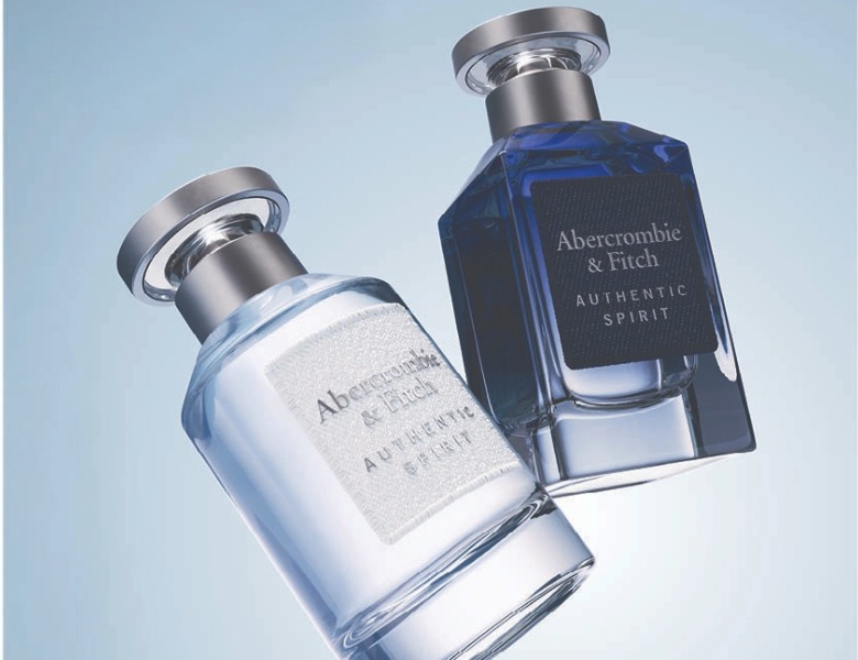 Her ses et kampagnebillede med to Abercrombie & Fitch Authentic Spirit-parfumeflakoner i lyseblå og mørkeblå nuancer. Til højre står teksten “Abercrombie & Fitch – Authentic Spirit” mod en lyseblå baggrund.