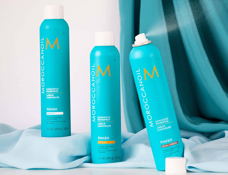 Her ses tre MoroccanOil i deres ikoniske turkise farve. Baggrunden har samme farve samt hvid.