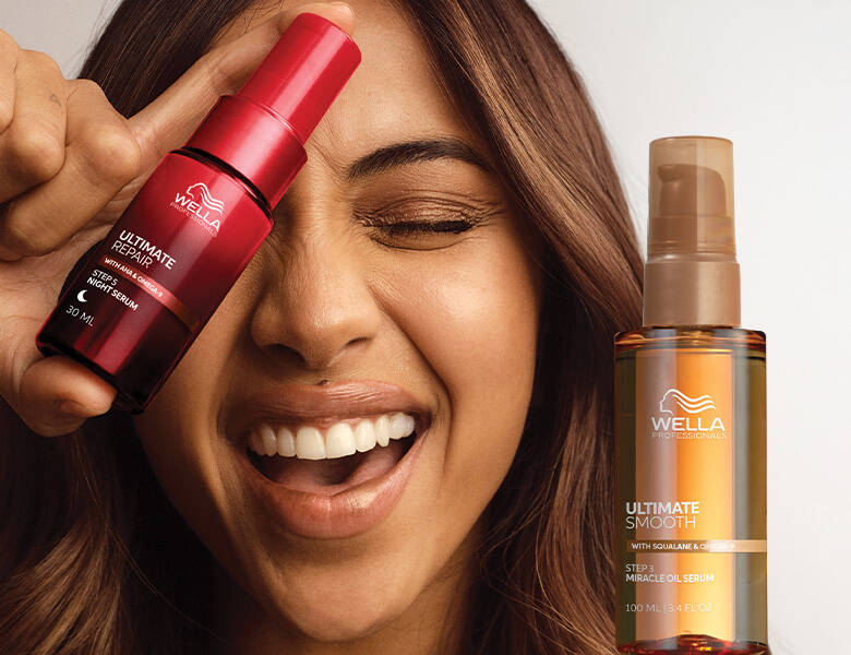 Her ses et billede af en person, der smiler og holder et hårserum fra Wella Professionals op foran ansigtet. Ved siden af ses endnu et produkt fra Wella Professionals med teksten “ULTIMATE SMOOTH”. Produkterne er i røde og gyldne nuancer.