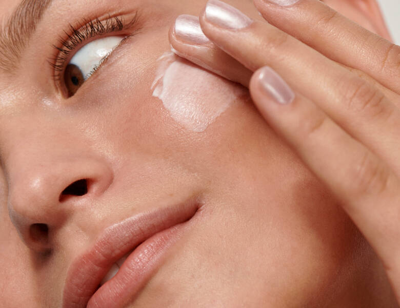 Her ses en kvindes ansigt. Hun smører creme på kinden.