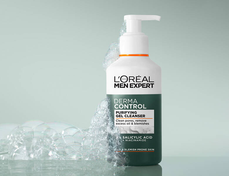 Her ses et L'Oréal Paris produkt u hvid og grøn. Baggrunden er blå-grøn og har sæbeskum.