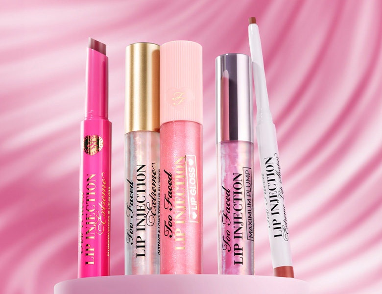 Her ses et billede med forskellige læbeprodukter fra Too Faced placeret mod en pink baggrund. På produkterne står teksten “Lip Injection”.