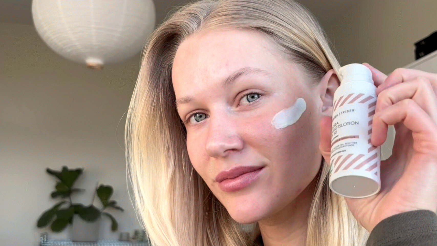 Her ses en person, der påfører Matas Striber Hydra Ansigtslotion SPF 50 på kinden og holder produktet op foran ansigtet.