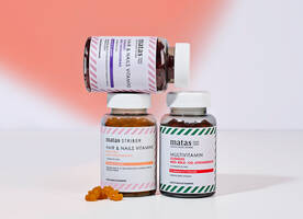 Her ses en rødlig og hvid baggrund med tre forskellige Matas Striber vitamin-vingummi-glas.
