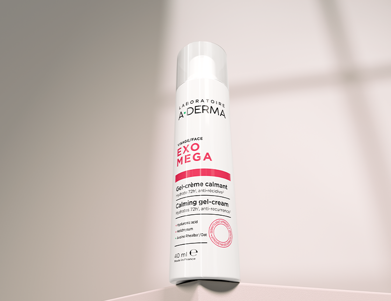 Her ses en A-DERMA Exomega ansigtscreme i hvid emballage med rosa detaljer på en lys baggrund.