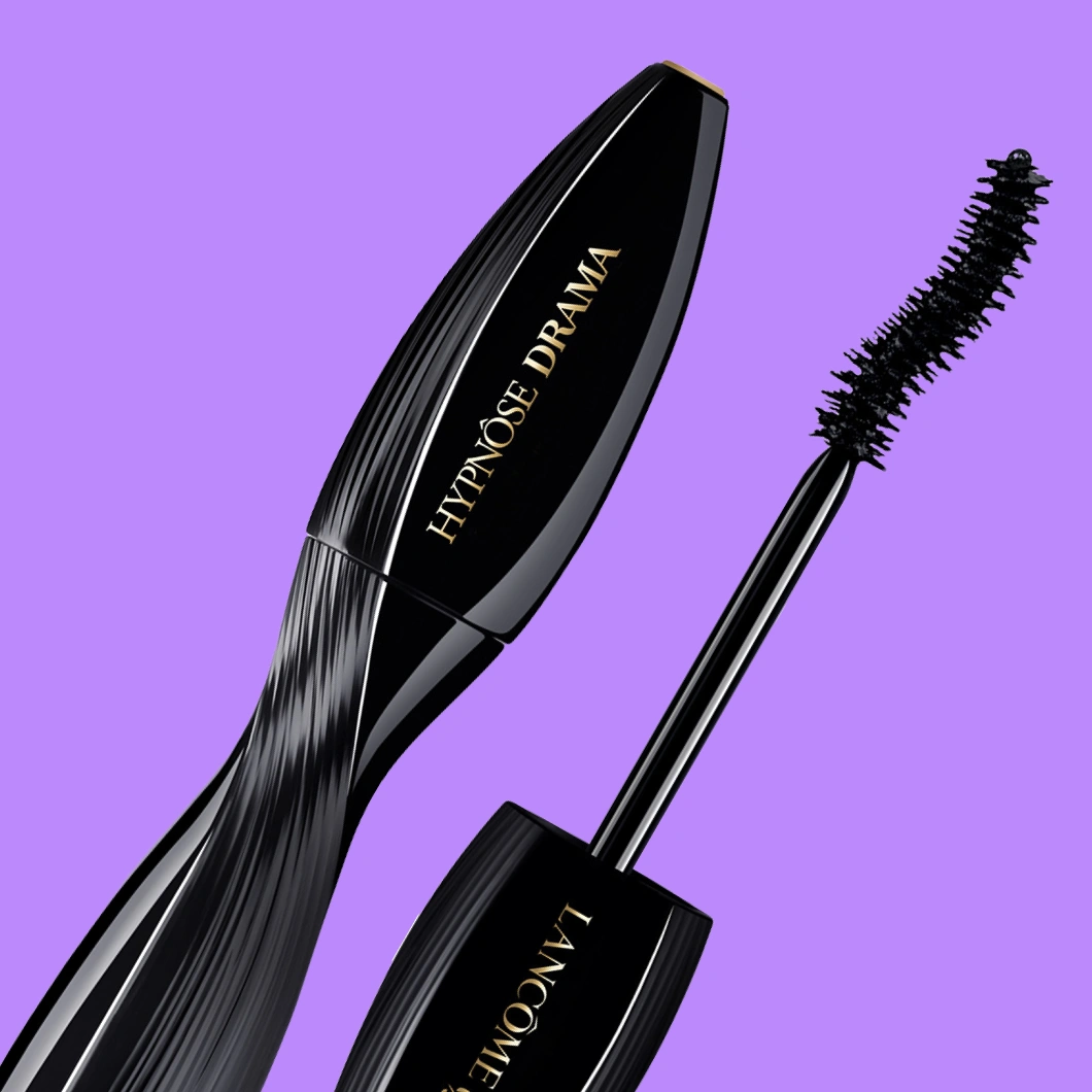 Musta Lancôme Hypnôse Drama -ripsiväri ja kaareva musta ripsiväriharja violetilla taustalla. Pakkauksessa näkyvät tekstit ”HYPNÔSE DRAMA” ja ”LANCÔME”.