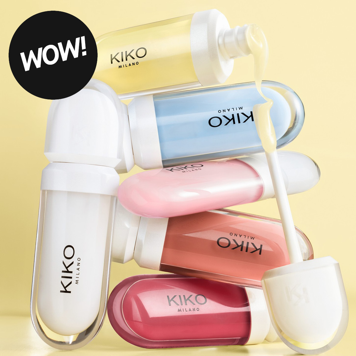 Flere KIKO MILANO-produkter i gjennomsiktige forpakninger med gult, blått, rosa, korallrødt og hvitt innhold mot en lysegul bakgrunn. En applikator med gult produkt vises sammen med en svart sirkel med den hvite teksten «WOW!».