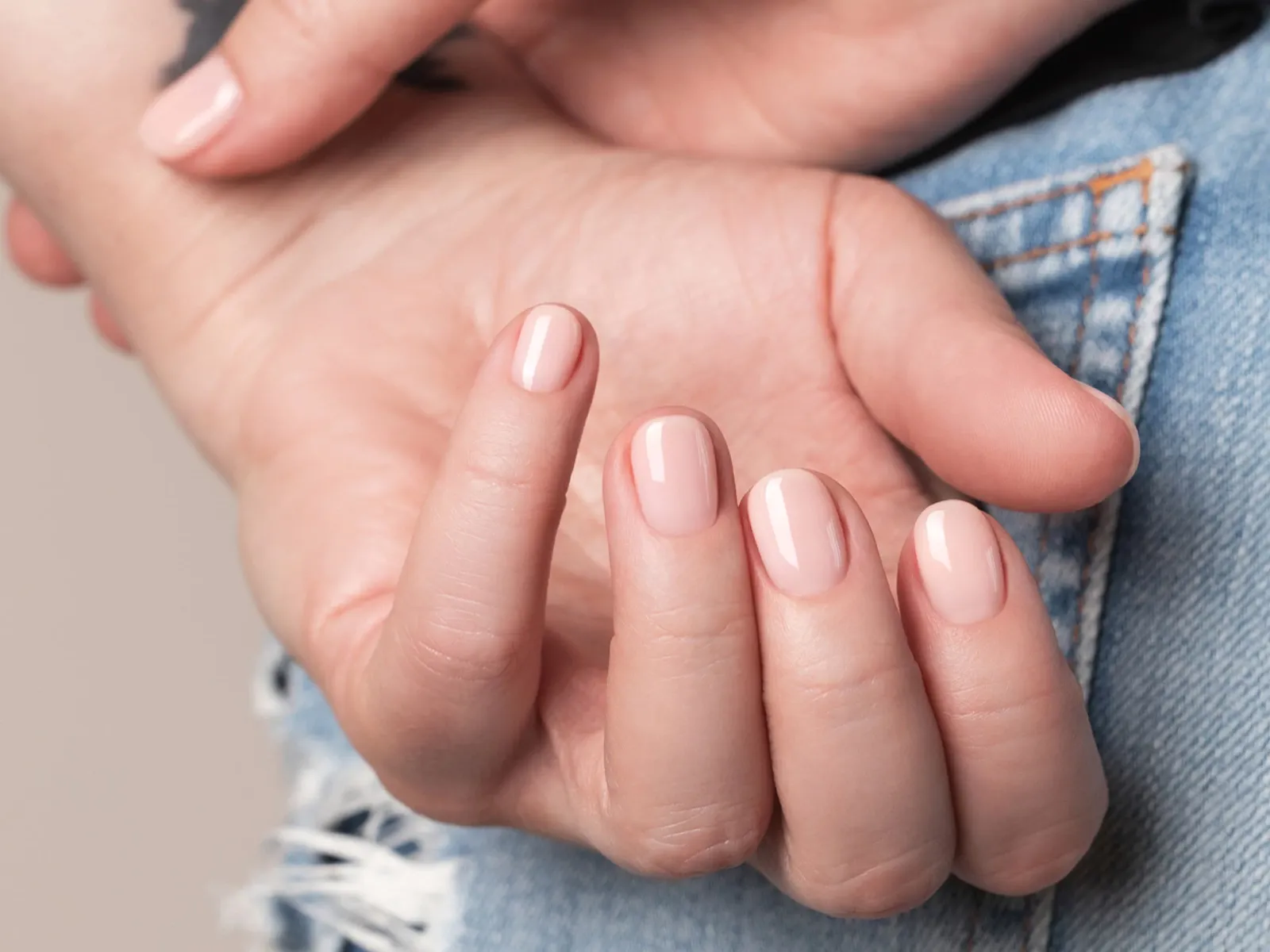 Närbild på en hand med ljusrosa nagellack.