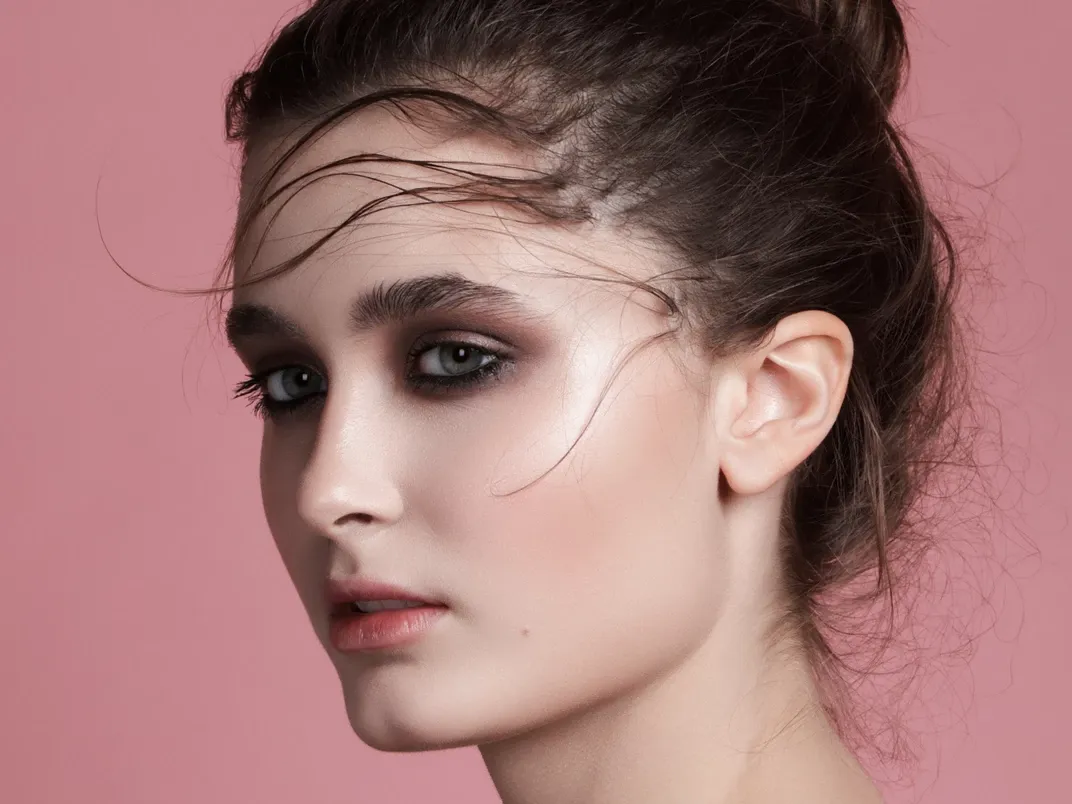 Kvinna med sotad ögonmakeup och löst uppsatt hår.