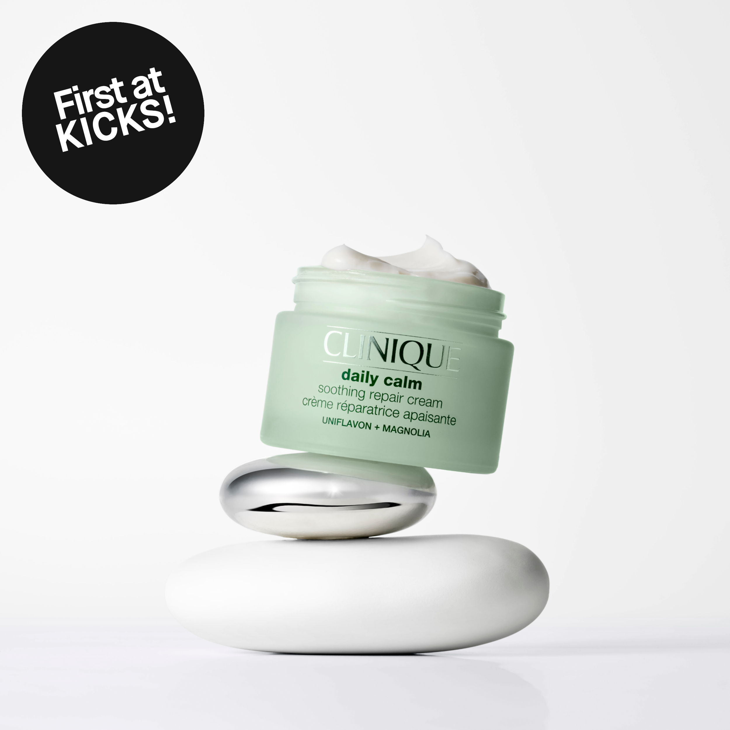 Clinique Daily Calm-rengöring och ansiktskräm mot ljus bakgrund bredvid balanserade stenar. Bilden innehåller texten ”First at KICKS!”.