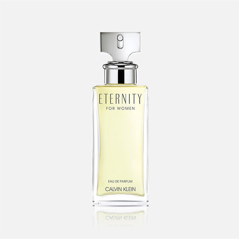 Transparent parfymflaska med ljusgul vätska från Calvin Klein med silverfärgad spraykork och texten "ETERNITY FOR WOMEN", "EAU DE PARFUM" och "CALVIN KLEIN".